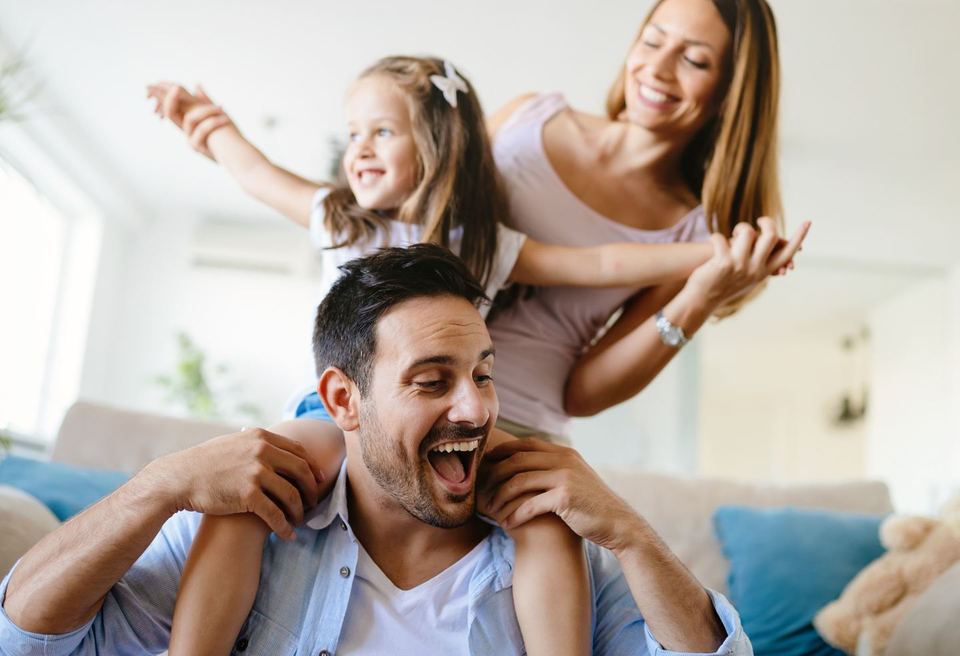 A happy family with two young children relaxing together in the bright living room of their new home.