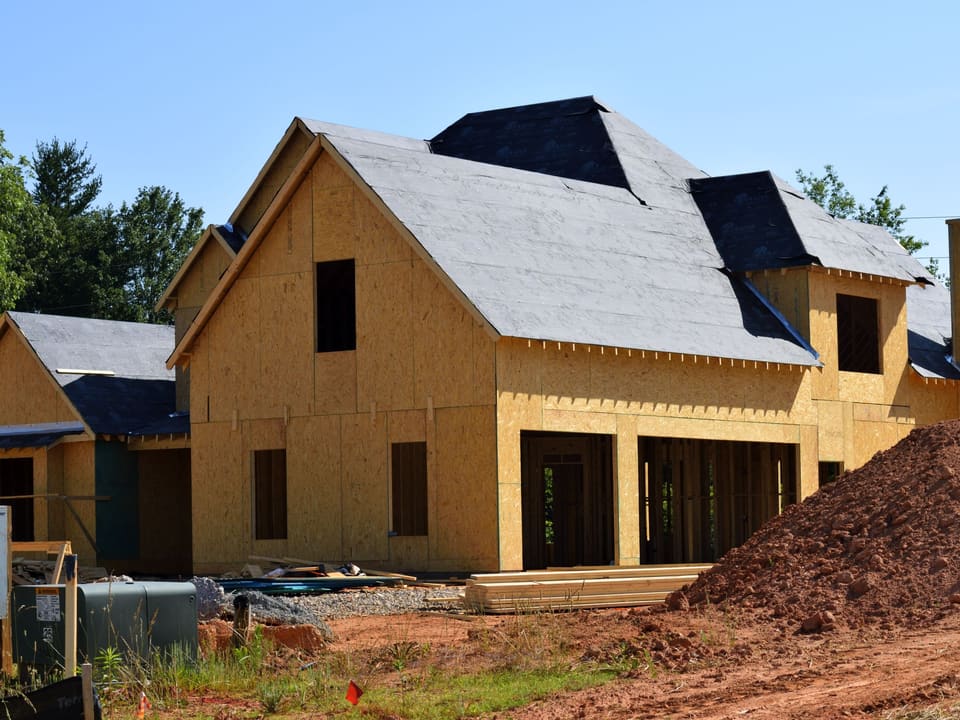 A new home under construction, framed and sheathed with the roof going on.