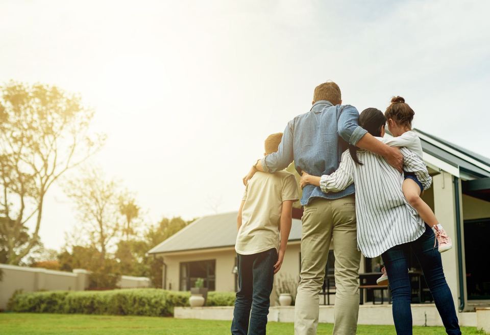 A family standing together in their backyard, looking toward their new North Texas home.