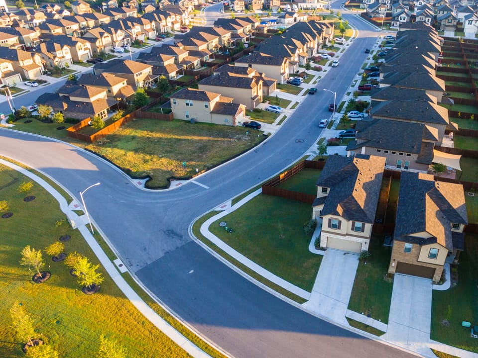 An aerial view of a newly built North Texas neighborhood with rows of homes along curving streets, representative of the area.