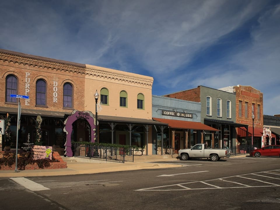 Restored two-story brick storefronts with awnings along the downtown square in Pilot Point, Texas.