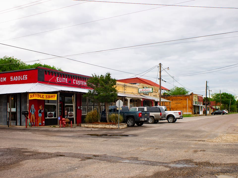 A custom saddle shop and storefronts along Main Street in downtown Tioga, Texas.