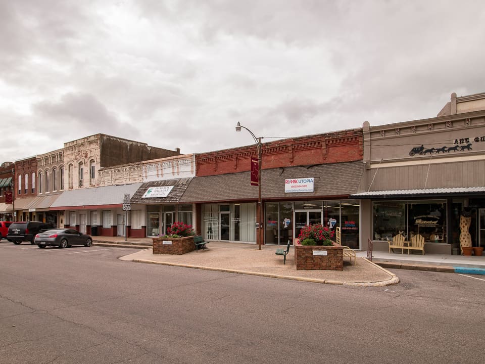 Historic brick storefronts and flower planters along downtown Whitesboro, Texas.